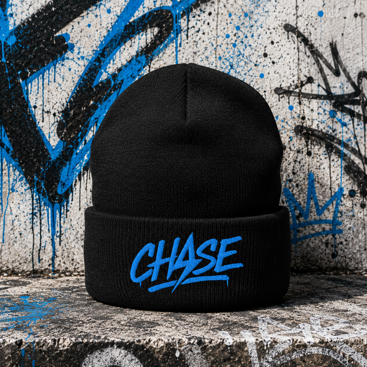 Black CHASE Core beanie with blue logo in front of a graffiti wall